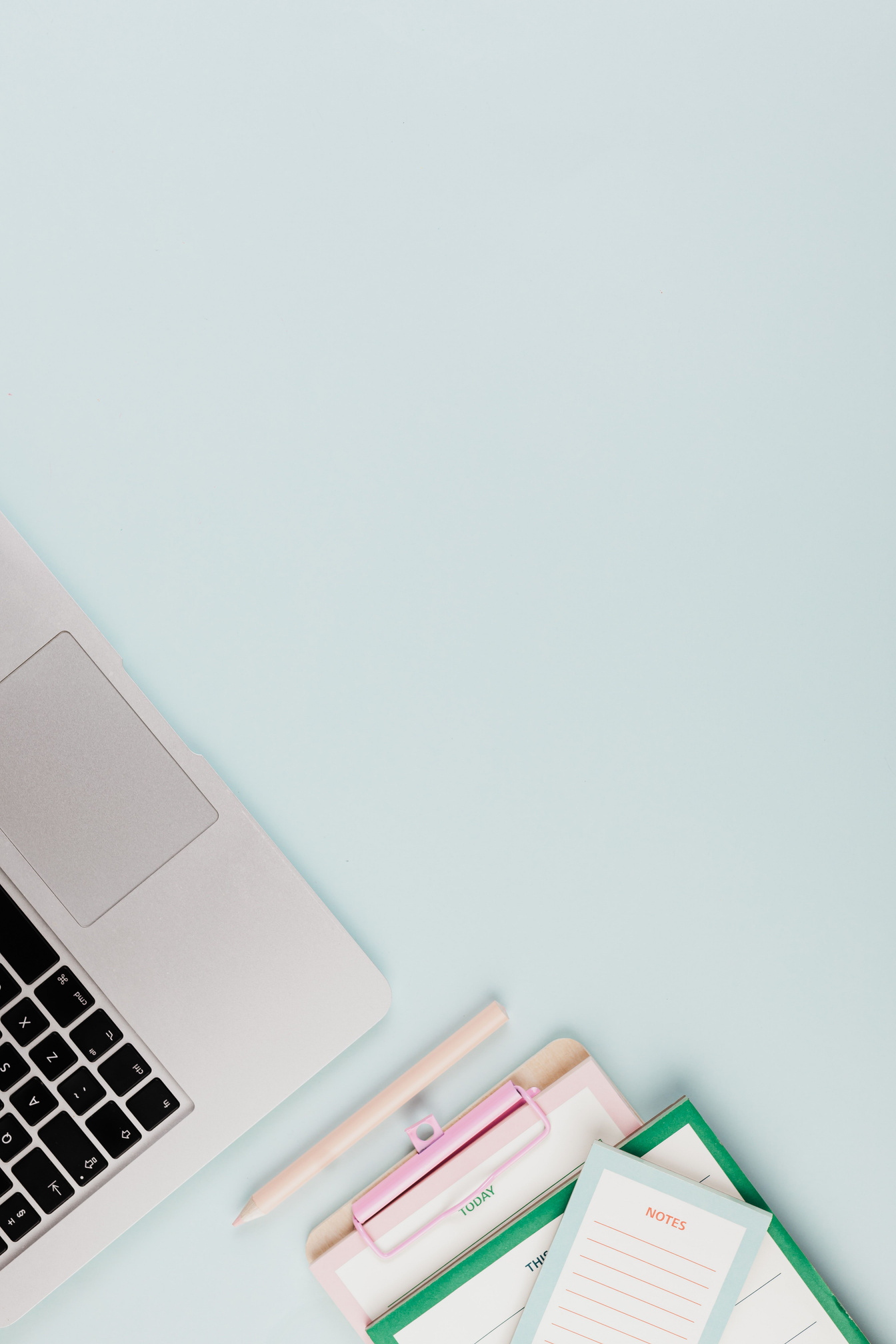 Pastellfarbener Arbeitsplatz mit Laptop und Unterlagen